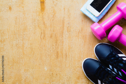 Fitness, healthy and active lifestyles Concept, sport shoes, dumbbells and smart phone on wooden background. copy space for text. Top view