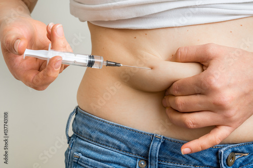 Diabetic woman with syringe inject insulin to her belly