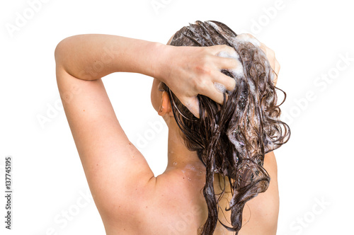 Attractive woman washing hair with shampoo in shower