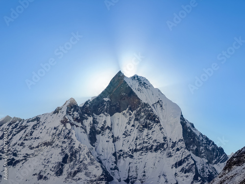 Mountain peak and rays of rising sun from behind him