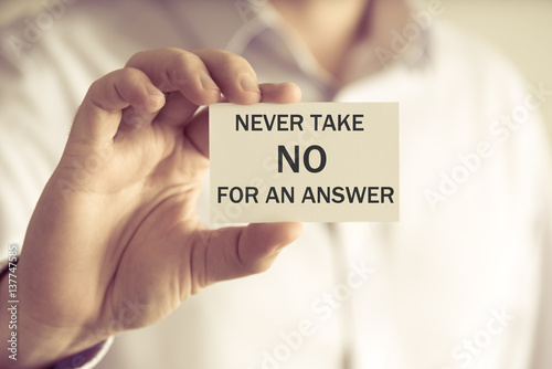 Businessman holding NEVER TAKE NO FOR AN ASNWER message card photo