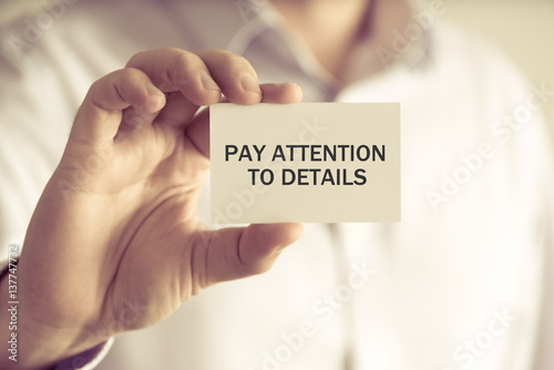 Businessman holding PAY ATTENTION TO DETAILS message card