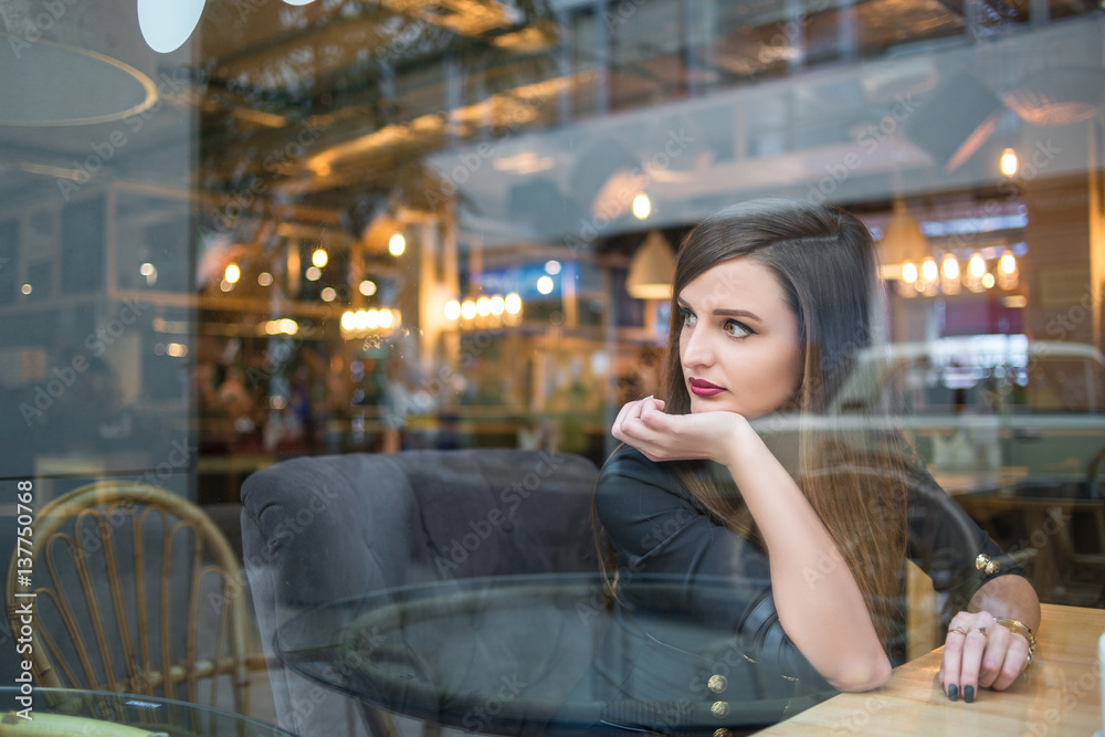 Beautiful young girl in blue glasses posing in cafe
