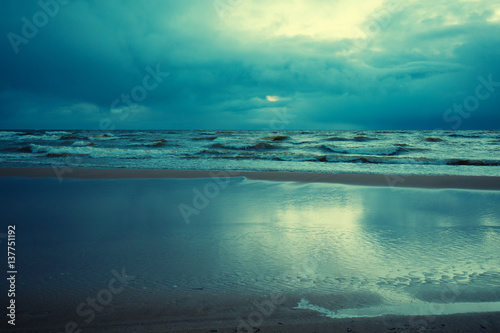 Fototapeta Naklejka Na Ścianę i Meble -  Early morning, sunrise over sea with cloudy sky. Stormy weather. Waves on the sea. Twilight time. 
