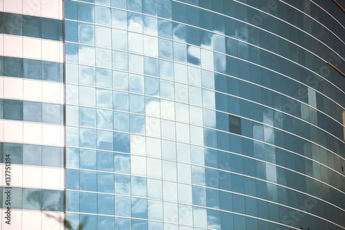 Cloudy sky mirrored in the windows of the office building. Vertical outdoors shot. photo
