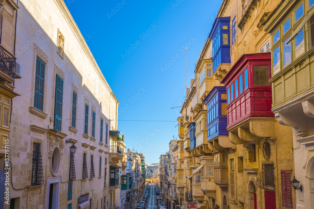 Valletta, Malta - Typical narrow street with colorful traditional windows and balconies and clear blue sky on a summer day