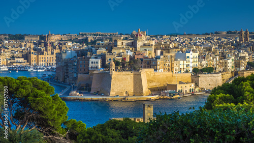 Valletta, Malta - The view from Valletta with trees, Island of Senglea, Gardjola Gardens with watchtower, the Grand Harbour with boats and ships and clear blue sky