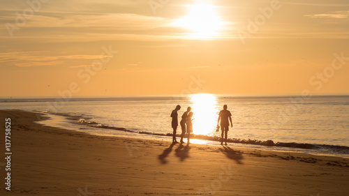 Groep mensen op het strand van Ameland tijdens zonsondergang photo