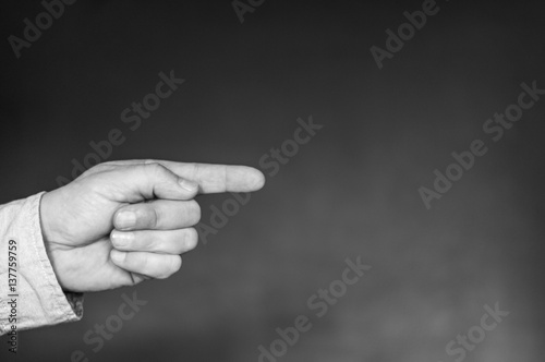 Hand mit ausgestrecktem Zeigefinger / Hand mit ausgestrecktem Zeigefinger vor dunklem Hintergrund mit Textfreiraum.