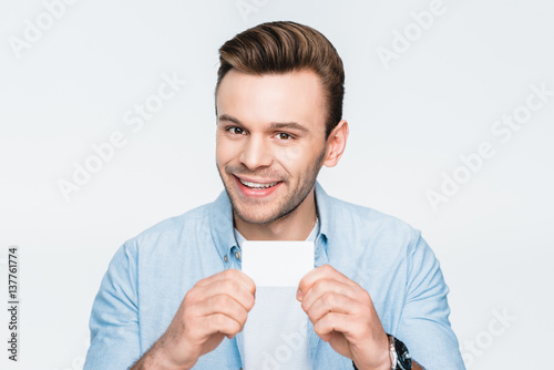 portrait of smiling man showing credit card and looking to camera on white