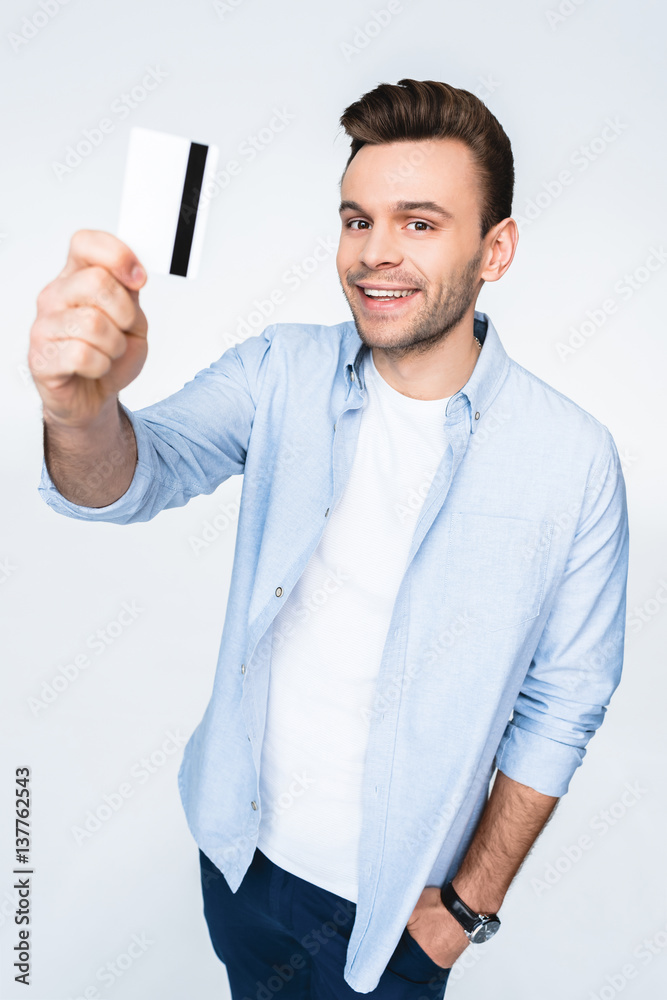 Happy young man holding credit card and smiling at camera Happy young man holding credit card and smiling at camera