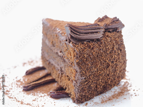 Food background. Piece of chocolate cake isolated on white. Slice of fresh brownie arranged on white plate. Close-up image. Selective focus on the front.