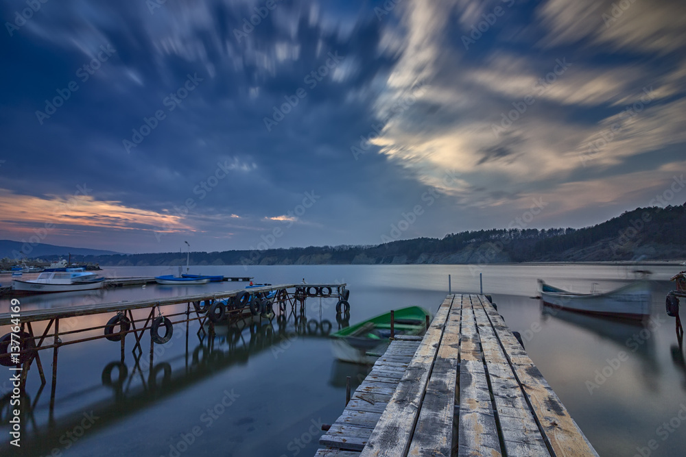 exciting long exposure seascape on harbor with wooden pier and boat