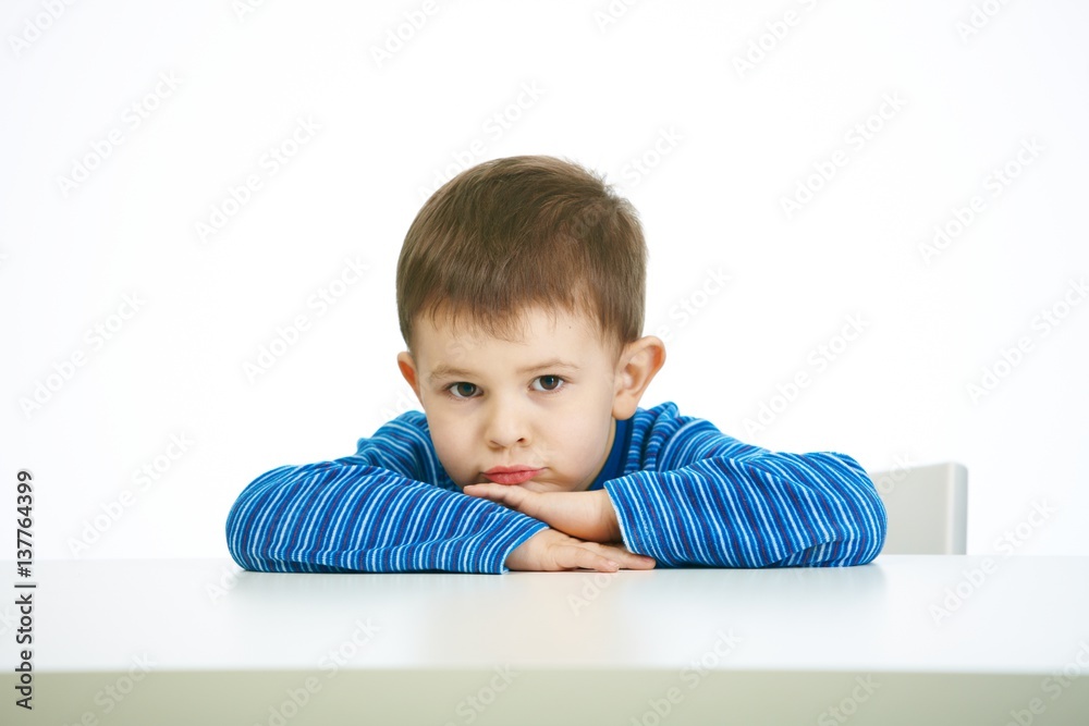 Portrait of sullen little boy sitting at table Portrait of sullen little boy sitting at table