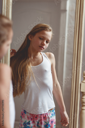 Teenage girl checking her face and body in the mirror