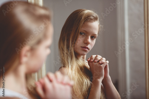Teenage girl checking her face and body in the mirror