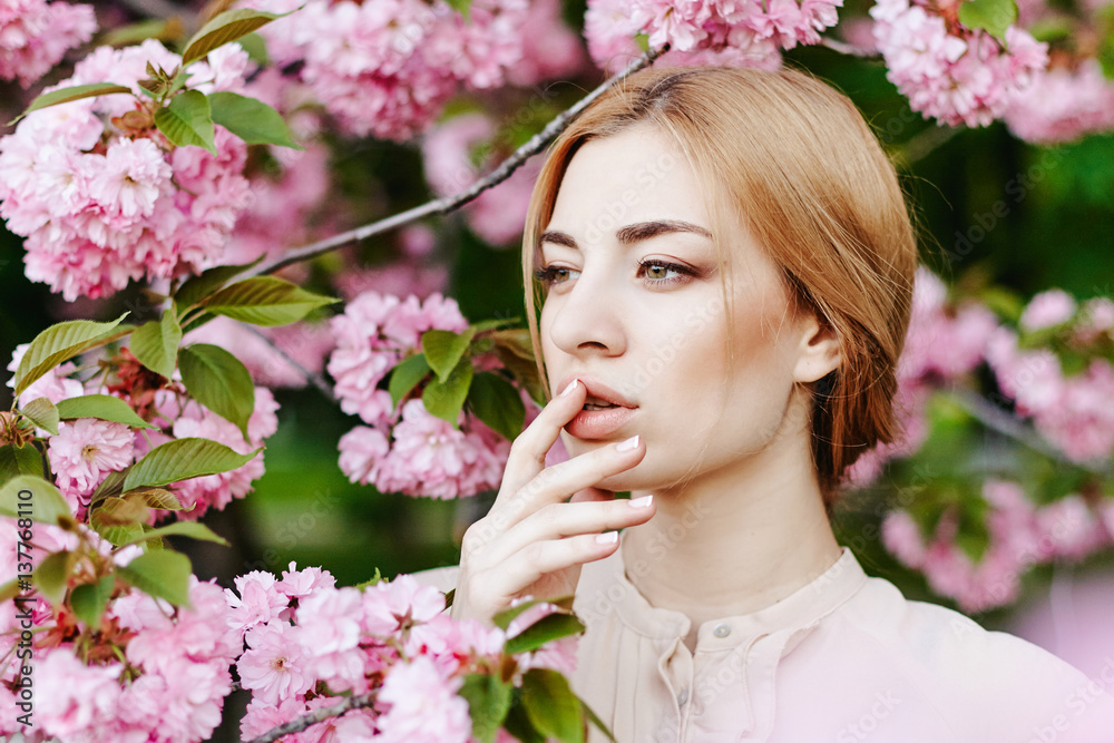 Obraz premium Spring portraits gorgeous young woman on cherry blossom background