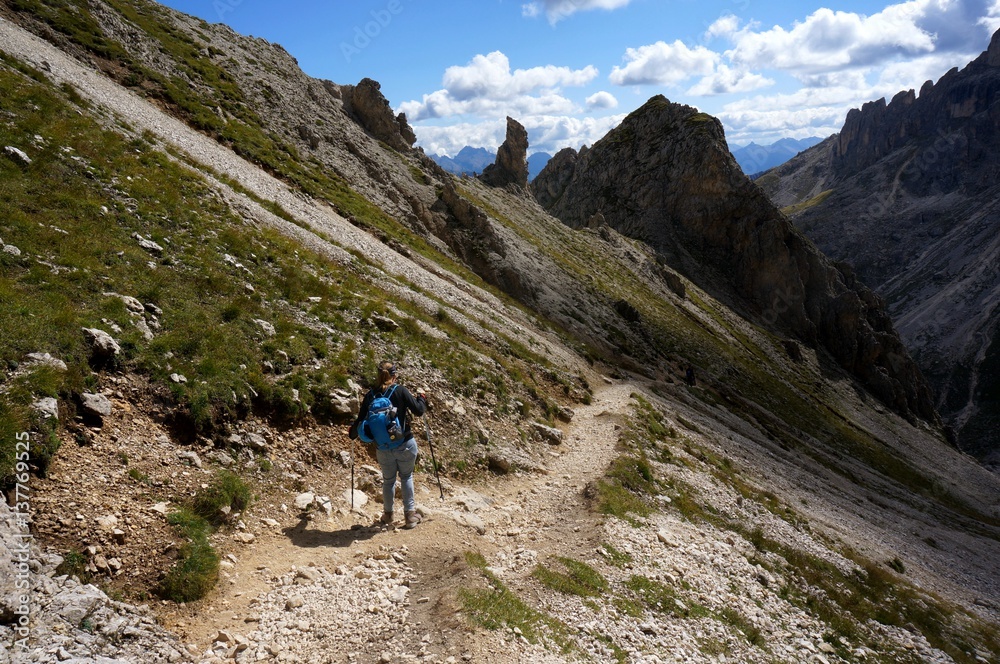 Wanderin alleine unterwegs mit Rucksack und Stecken in den Bergen in felsiger Gebirgslandschaft
