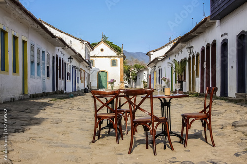 Fototapeta Naklejka Na Ścianę i Meble -  Street scene with table and chairs in historic colonial town Paraty, Brazil