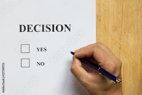 Decision paper with yes and no choice with man hold the pen on wood background