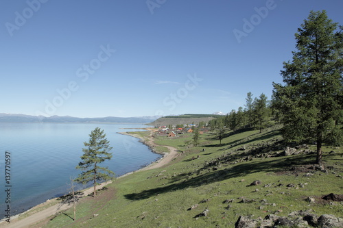 A dirt road along the shore of lake Hovsgol Relict larch on the slope of a coastal hill in the background of the bowl of the lake and the far shore on the horizon, road , village, Turt – the administr photo