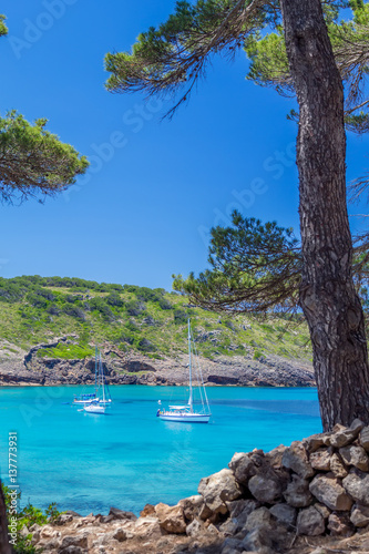 Beautiful Menorca island cove with yachts floating on turquoise water