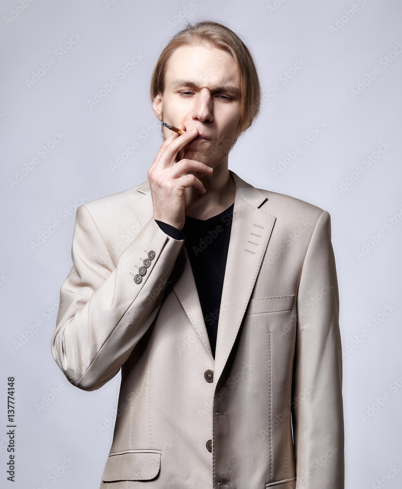slijm Oraal Reclame Stockfoto Young blond male model in beige man suit smoking | Adobe Stock