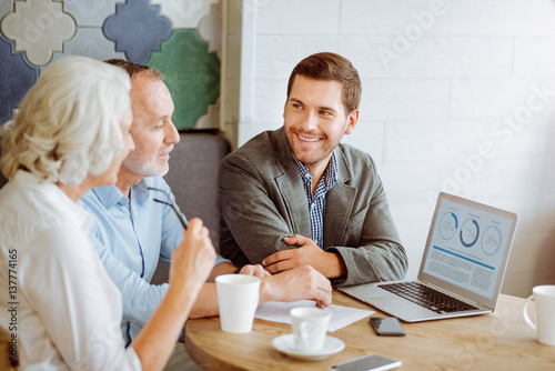 Professional smiling insurance manager talking with aged couple