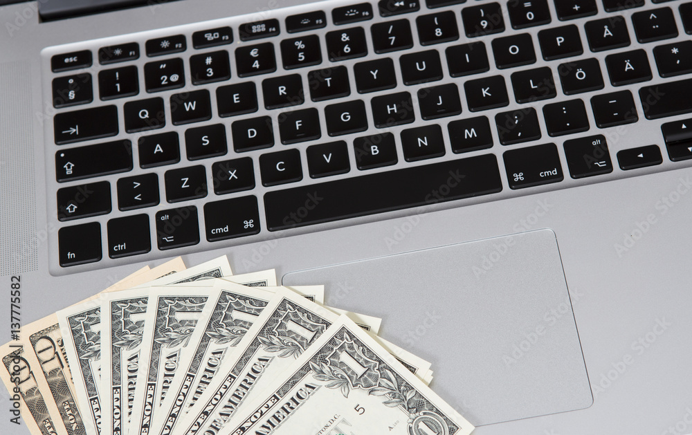 US dollars and a modern laptop. Business and online shopping concept image. US dollars and a modern laptop. Business and online shopping concept image.