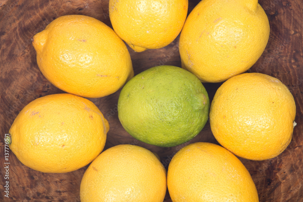 Ripe organic lime and lemons in wooden bowl like background