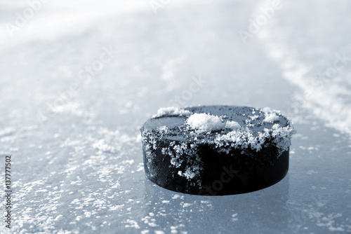 Hockey puck lying on a ice rink.