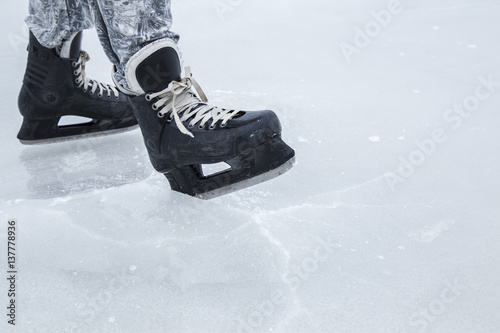 Man skating with black skates on the ice area at the seashore in winter day. Weekends activities outdoor in cold weather.