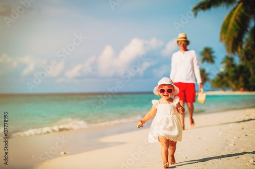 little girl walking on the beach with father