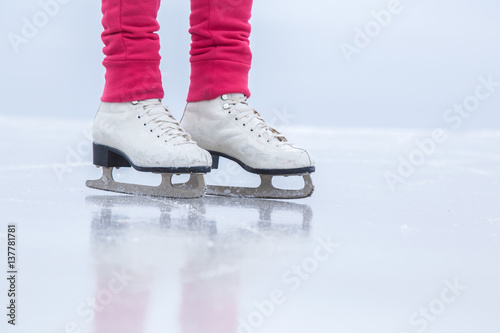 Woman skating with white skates on the ice area at the seashore in winter day. Weekends activities outdoor in cold weather.