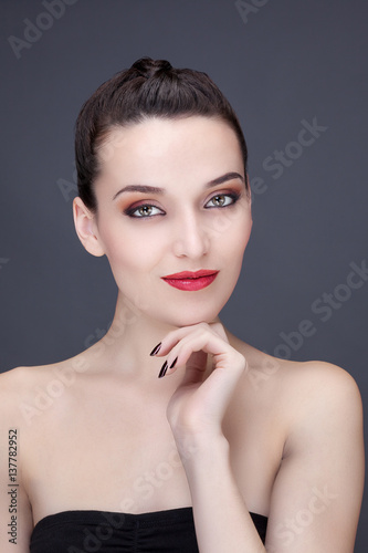 Portrait d'une jeune femme souriante, une main sous le menton, le regard vers l'objectif