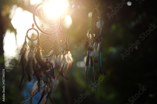 Soft focus Dream Catcher with a flare from the sun set on the background bokeh nature. Native american dream catcher. (Vintage style) boho chic, ethnic amulet.