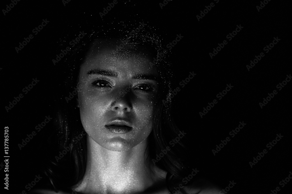 Studio portrait of a beautiful girl with long hair. Glitter on your face. Beautiful eyes. Dark background. Mysterious, mystical,