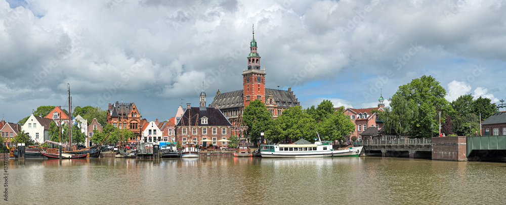 Leer, Germany. Panoramic view from Leda river on City Hall in Dutch Renaissance style, Old Weigh House in Dutch classical Baroque style, Tourist Harbor and Bridge of Erich vom Bruch. - obrazy, fototapety, plakaty 