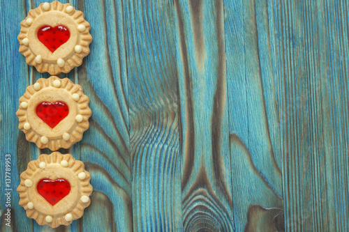 Sweet jelly cookies with red filling like a heart on the blue wooden table