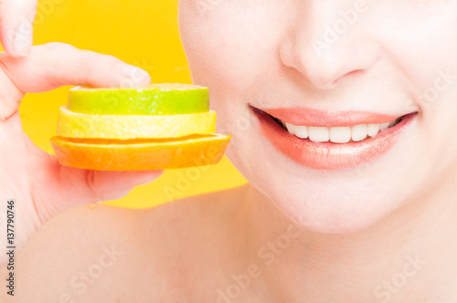 Happy model in closeup holding slices of fruits