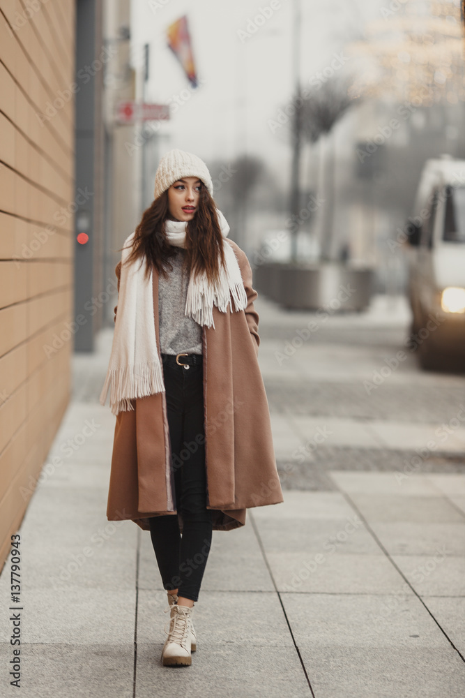 Girl walking near the wall and looking at camera. Blur yellow background