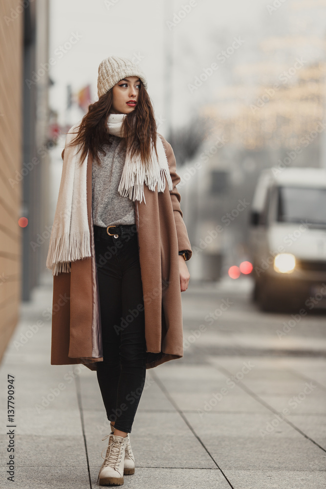Girl walking near the wall and looking at camera. Blur yellow background Girl walking near the wall and looking at camera. Blur yellow background