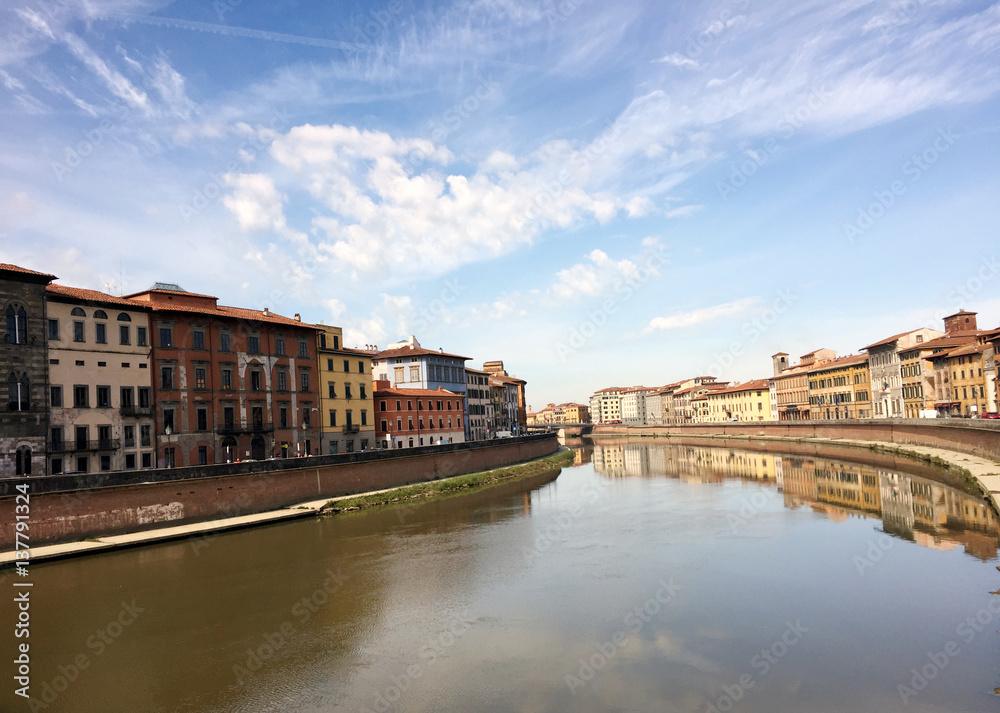 Landscape view of blue sky, river and buildings in Pisa, Italy
