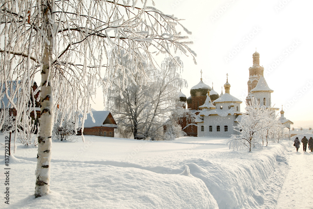 Obraz premium Orthodox monastery behind of bare hoary birch in deep snow