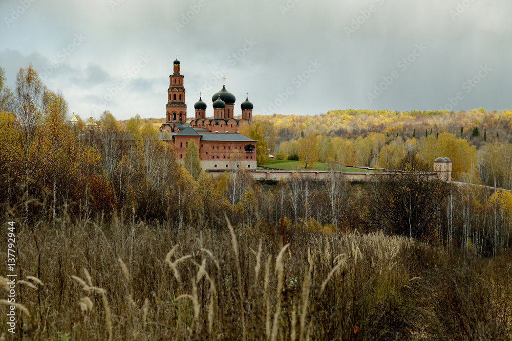 Cloudy sky over Orthodox monastery and the autumn forest