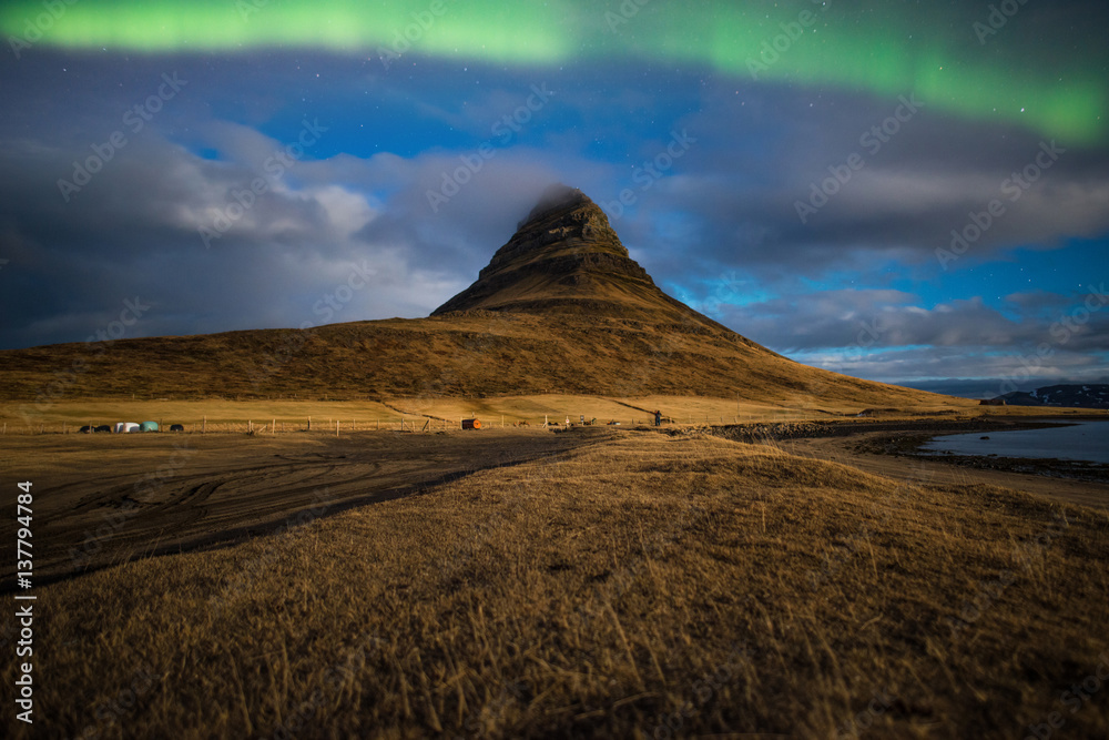 Obraz premium Aurora or the Northern light over the Kirkjufell mountain the iconic famous mountain in triangle shape in the west region of Iceland.