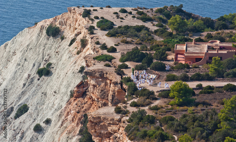 Holiday on the edge of a cliff. People in white at Ibiza.