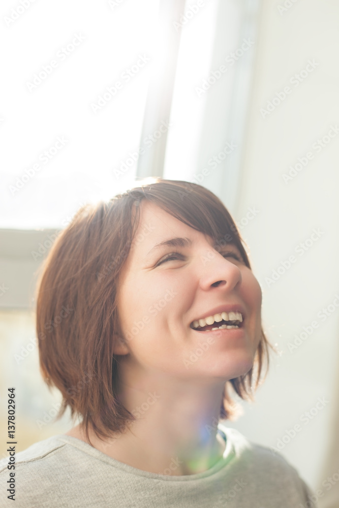 Happy girl laughs because of good news. She looks up. Lens flare effect