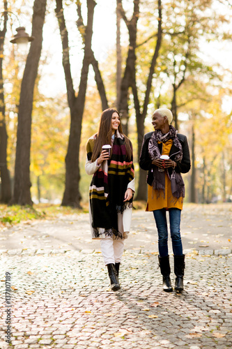 Multiracial female friends walking in teh autumn park