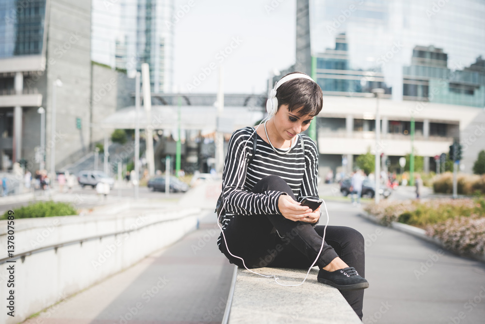 Young beautiful caucasian short brown hair woman with smart phone hand hold listening music - music, technology, social network concept Young beautiful caucasian short brown hair woman with smart phone hand hold listening music - music, technology, social network concept